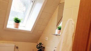 Un baño con inodoro, lavamanos y ventana con plantas.