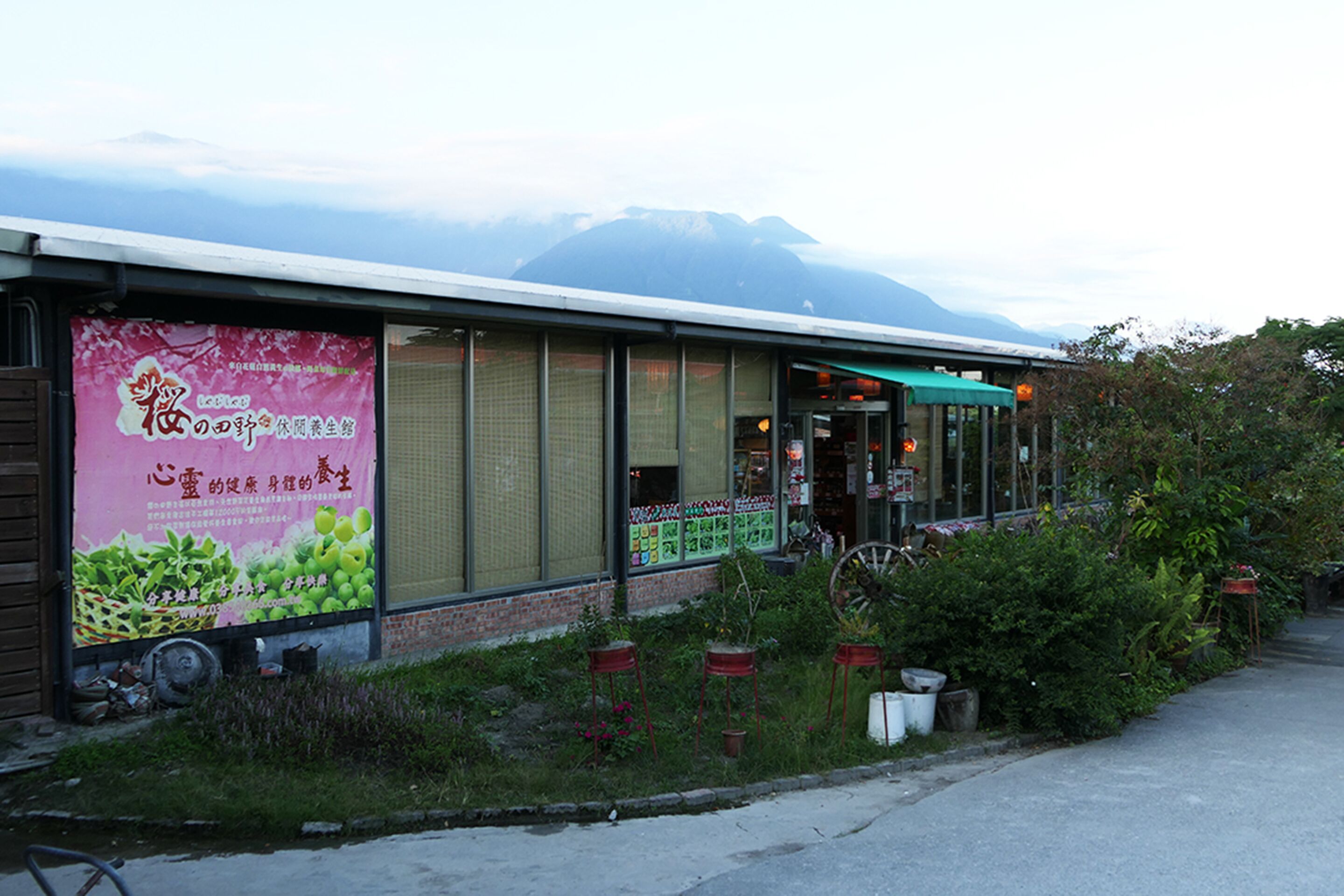 A building with a large poster advertising a health-related product, a covered outdoor seating area, and a mountain in the background.