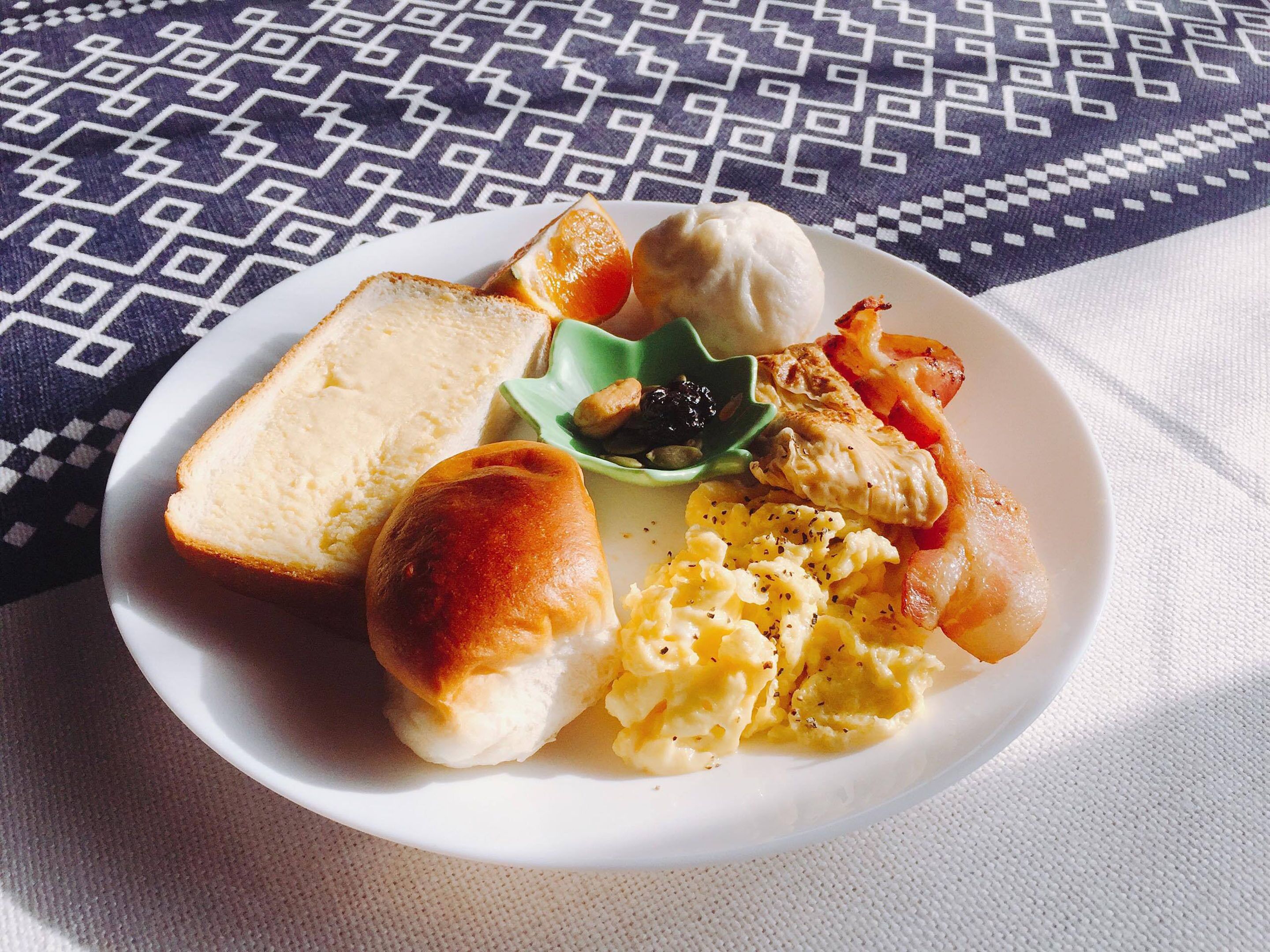 A plate with toast, a muffin, scrambled eggs, and a small green dish with a condiment.