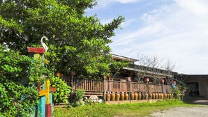 A rustic building with a wooden fence, a colorful gate, and a row of large vases. - Sakura B&B (Ji'an)