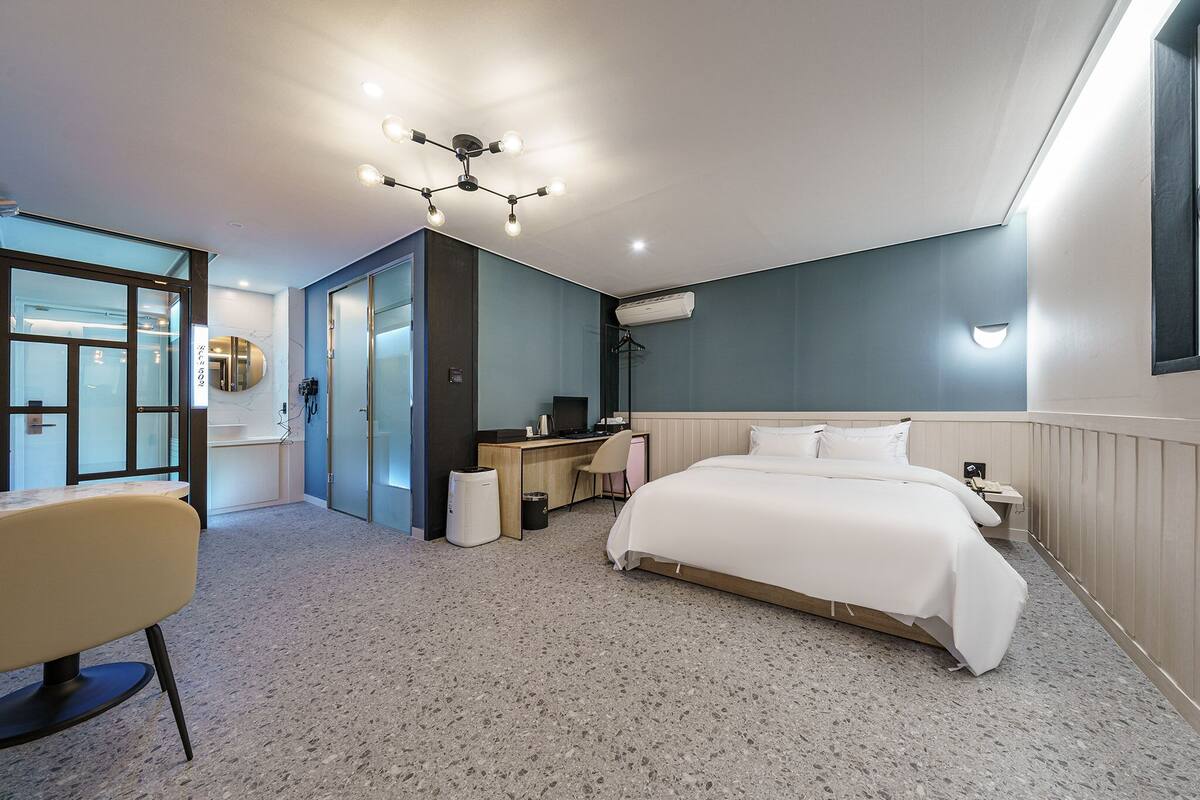 A modern hotel room with a large bed, a desk, and a chair.