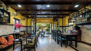 A restaurant with a central dining area, booths, and a bar area with shelves. - Hoi An Coco Viet Homestay (Da Nang)