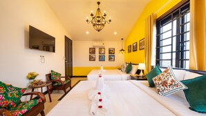 A hotel room with a bed, a sofa, a chair, a TV, and a chandelier. - Hoi An Coco Viet Homestay (Da Nang)