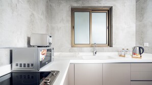 A modern kitchen with a built-in microwave, stove, and sink. - AFAM Residence (Dammam)