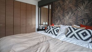 A bedroom with a large bed, a wardrobe, a nightstand, and a mirror.