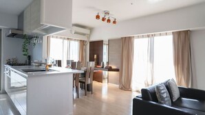 A modern apartment with a central kitchen, dining area, and a living room with a sofa.