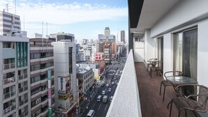 A high-rise building with a balcony overlooking a busy urban street.