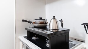 A compact kitchen with a stove, a kettle, and a pot on the countertop. - Crystal Exe Nipponbashi St36 (Osaka)