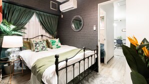 Une chambre à coucher moderne avec un mur en briques, un lit avec un cadre en métal, un miroir rond et une plante en pot.