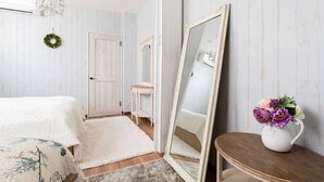 A bedroom with a bed, a dresser, a mirror, a chandelier, and a vase with flowers. - Ota Building St31&32 (Osaka)