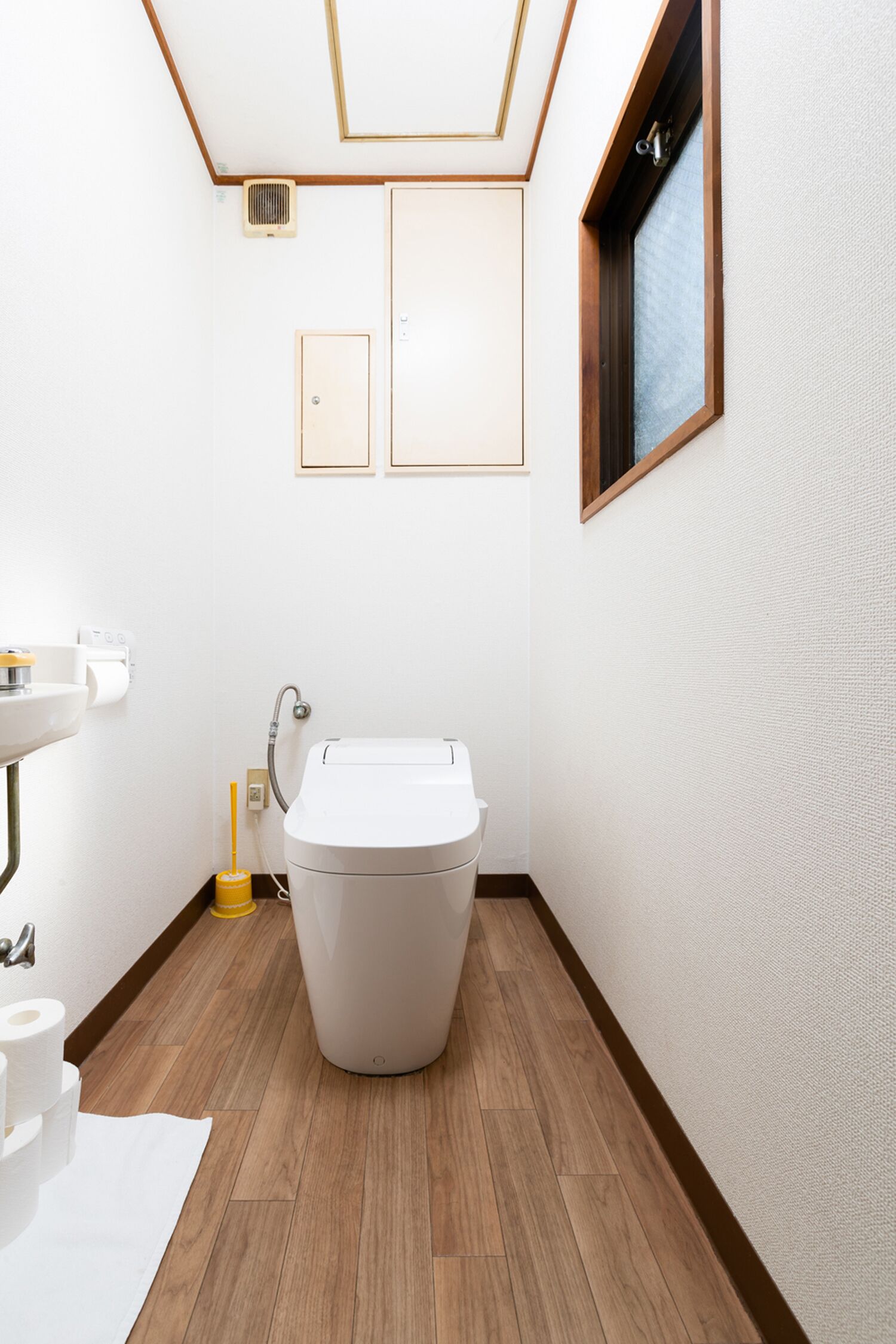 A small, clean bathroom with a toilet, sink, and window.