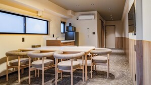 Ein kompaktes Hotelzimmer mit Essbereich, ausgestattet mit einem Holztisch und sechs gepolsterten Stühlen.