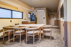 A compact hotel room with a dining area featuring a wooden table and six upholstered chairs.