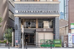 Um edifício moderno com uma placa que diz 'APARTMENT HOTEL 11', indicando um hotel-residência.