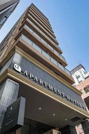 A multi-story building with a sign that reads 'APARTMENT HOTEL.'
