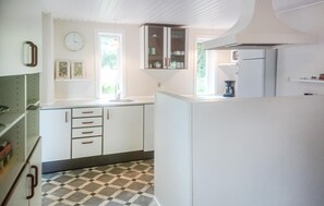 Compact kitchen with a checkered floor, white cabinetry, sink, and stove.