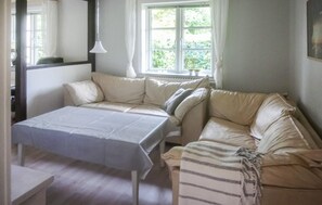 Relax in a spacious room with a sofa against a window, a small table, and a clean, minimalist design.