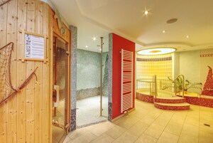 A spa area with a wooden wall, a glass door leading to a shower, and a red wall with a tiled bench.