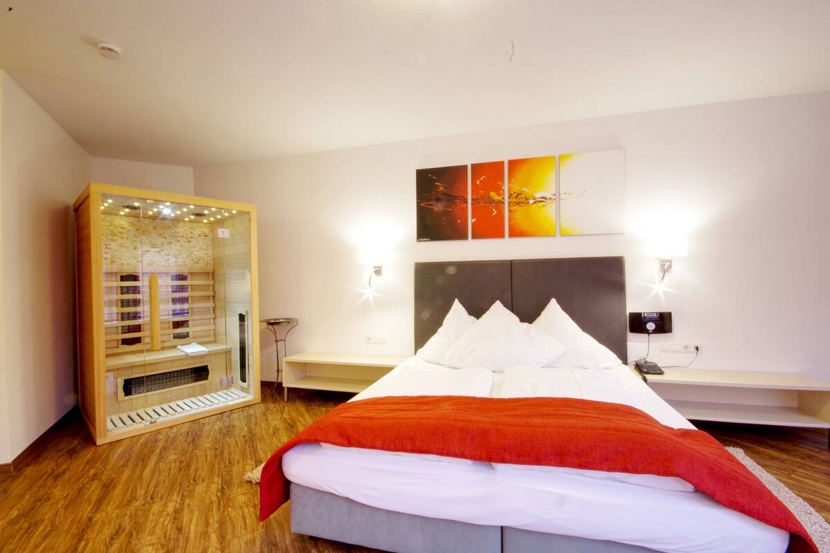 Quarto de hotel moderno com uma cama grande, um armário de madeira e uma prateleira fixada na parede.