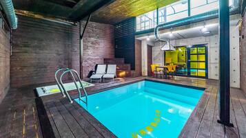 A modern indoor pool with wooden decking and a clear blue pool.