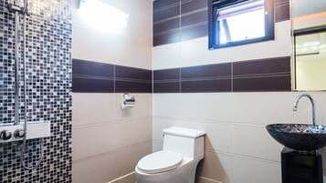 A bathroom with a toilet, bidet, and a sink.