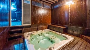 A wooden spa room with a large hot tub, wooden walls, and a window overlooking a snowy outdoor area. - Vista Hill Pool Villa (Gapyeong)