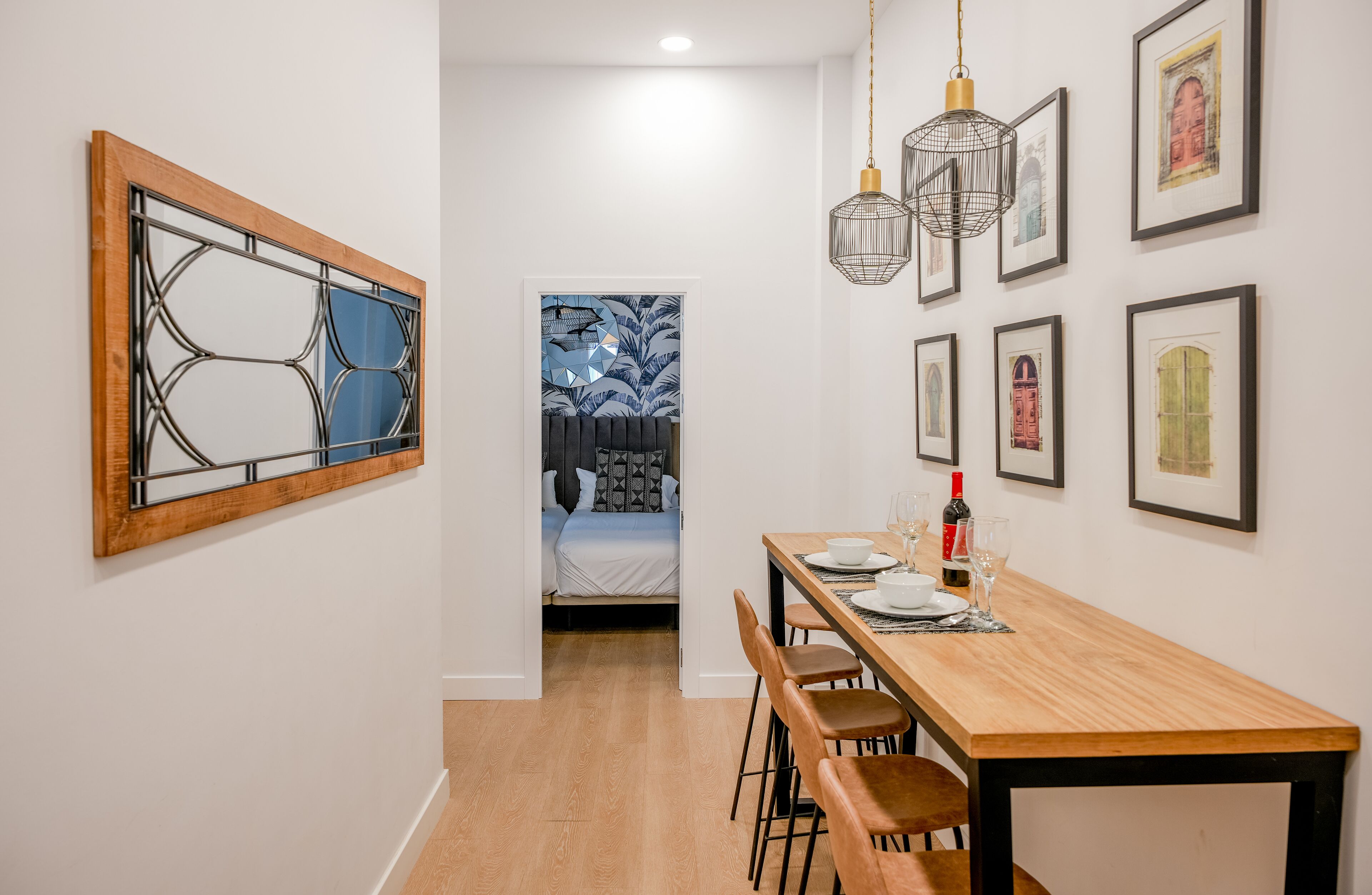 A modern dining area with a wooden table, chairs, and hanging pendant lights.