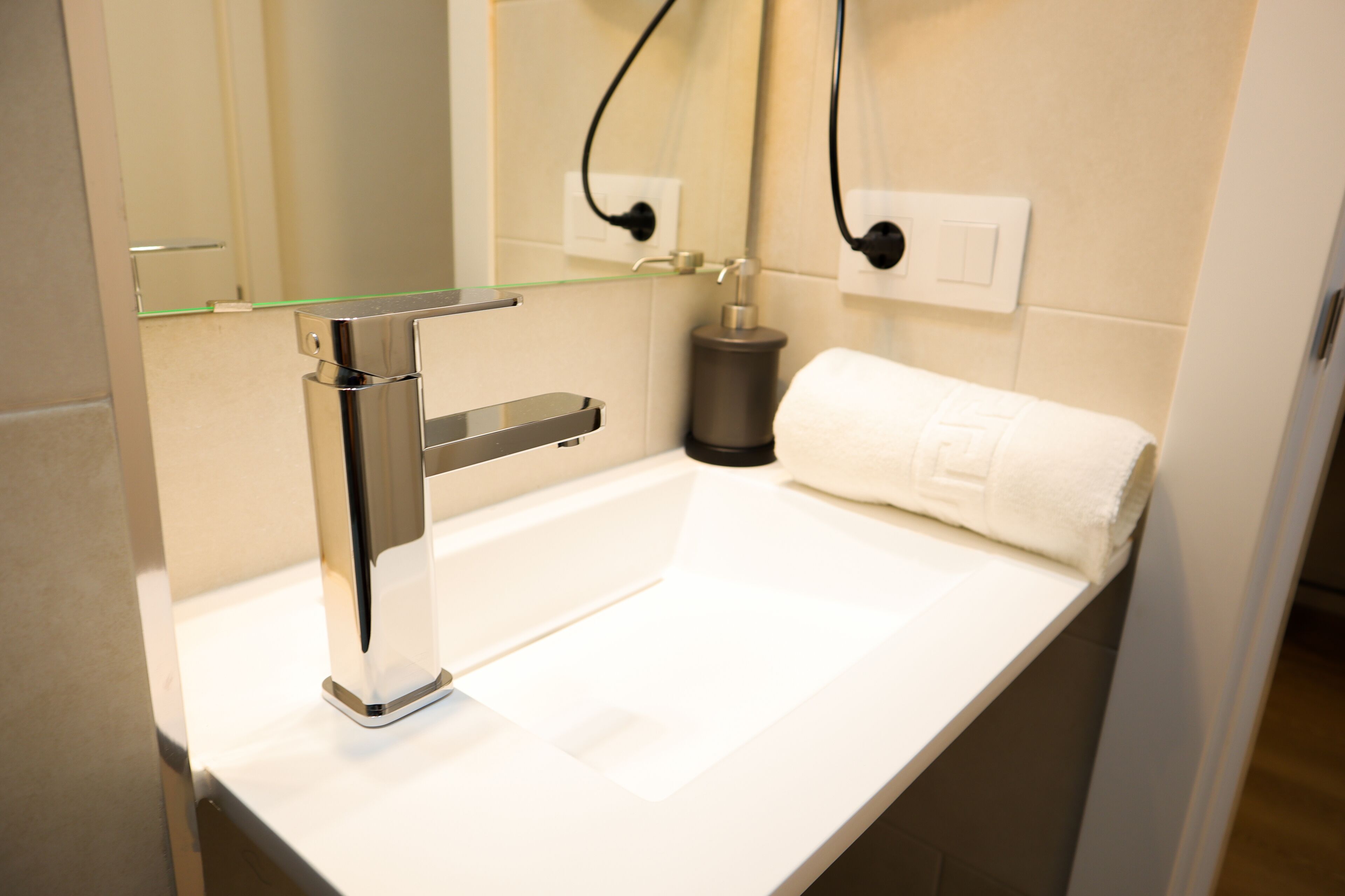 Ein modernes Badezimmer mit einem Chromarmaturen, einer Glasablage und einem weißen Handtuch.
