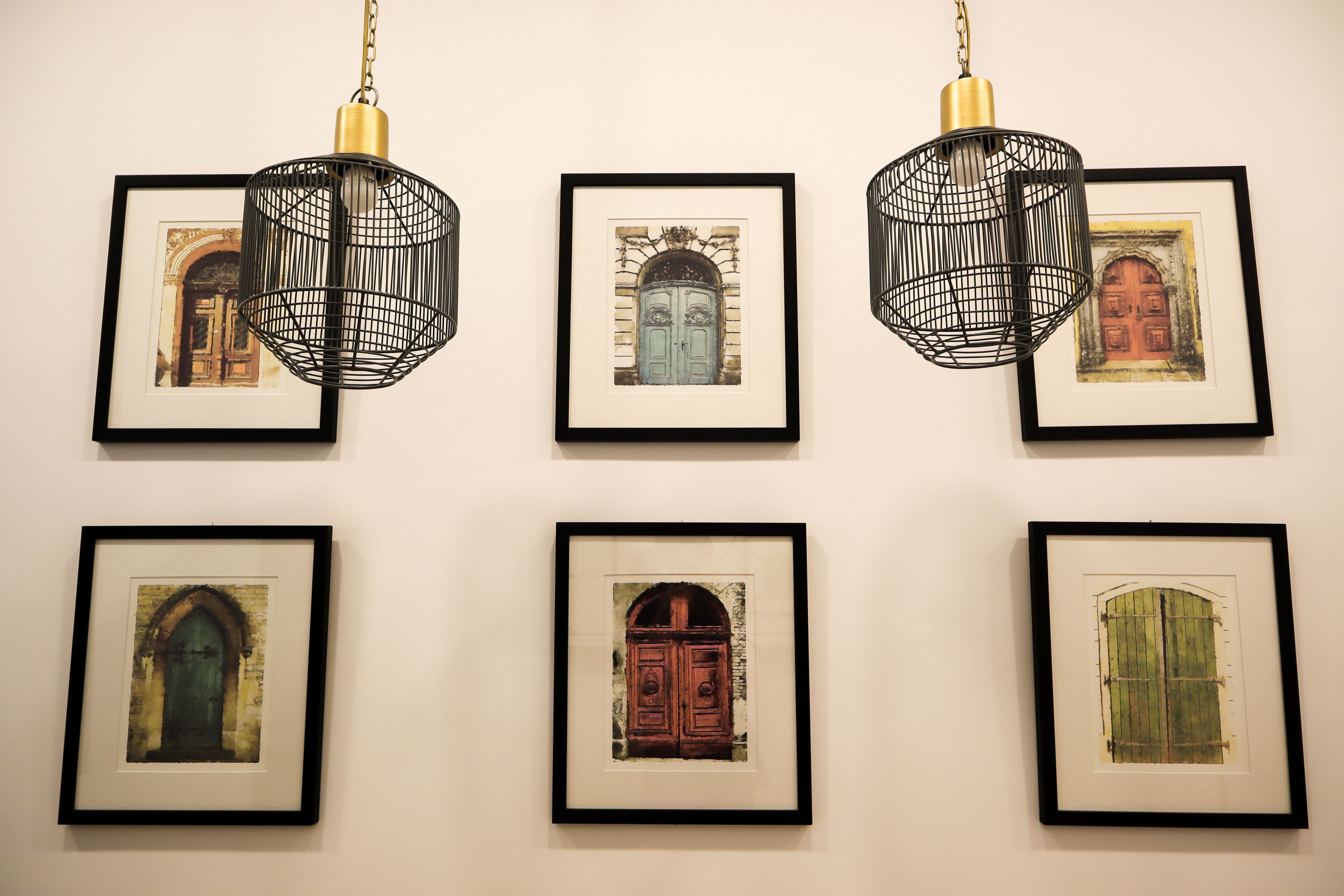 Seis ilustraciones de puertas enmarcadas en una pared, cada una con un marco negro y colgadas del techo.