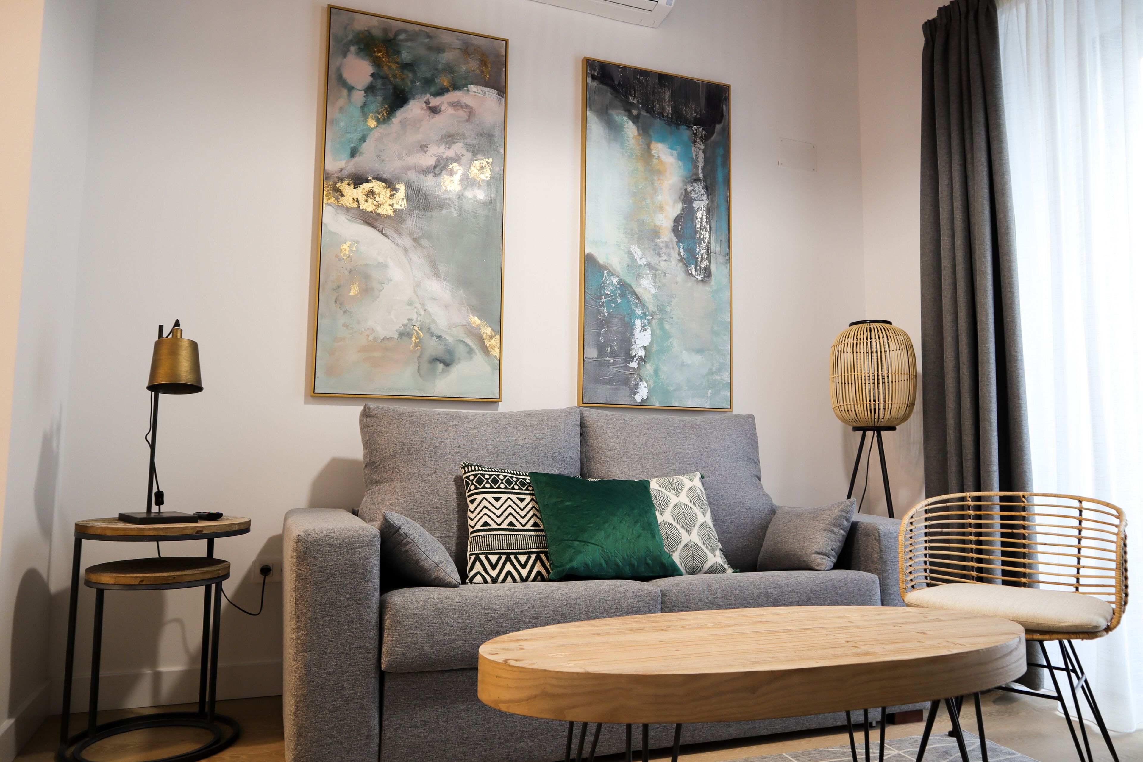 A modern living room with a grey sofa, a round wooden coffee table, and two abstract paintings on the wall.