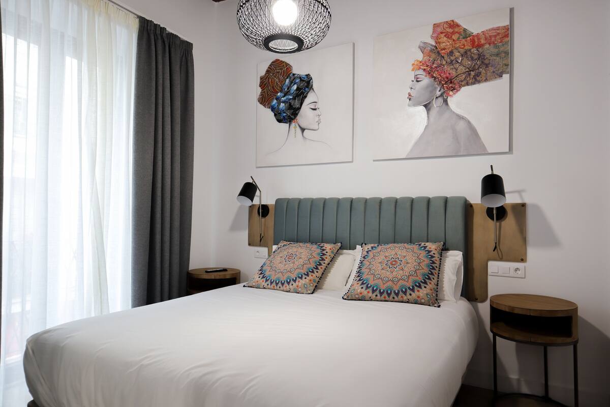 A neatly arranged bedroom with a large bed, two wall-mounted lamps, and two side tables.