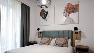 A neatly arranged bedroom with a large bed, two wall-mounted lamps, and two side tables.