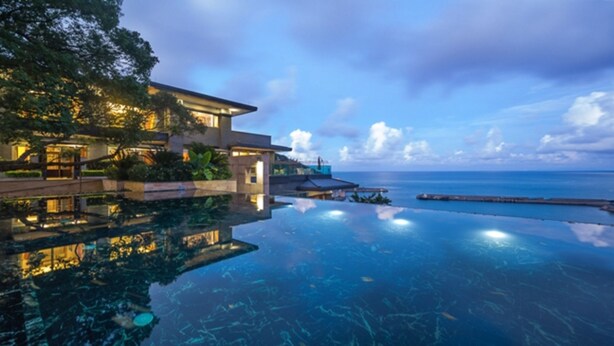 Un resort lujoso con piscina infinita con vistas al mar.
