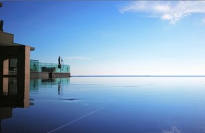 A modern building with a glass facade overlooking a calm body of water.