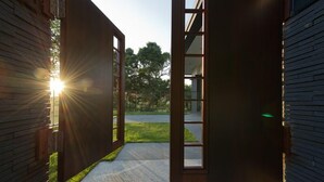 Una entrada de edificio moderna con puerta de vidrio y pared de ladrillo.