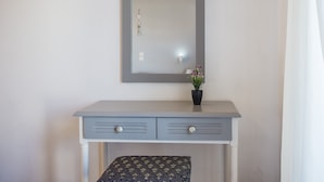 Un piccolo mobile bagno grigio chiaro con specchio, due cassetti e una piccola pianta in vaso.