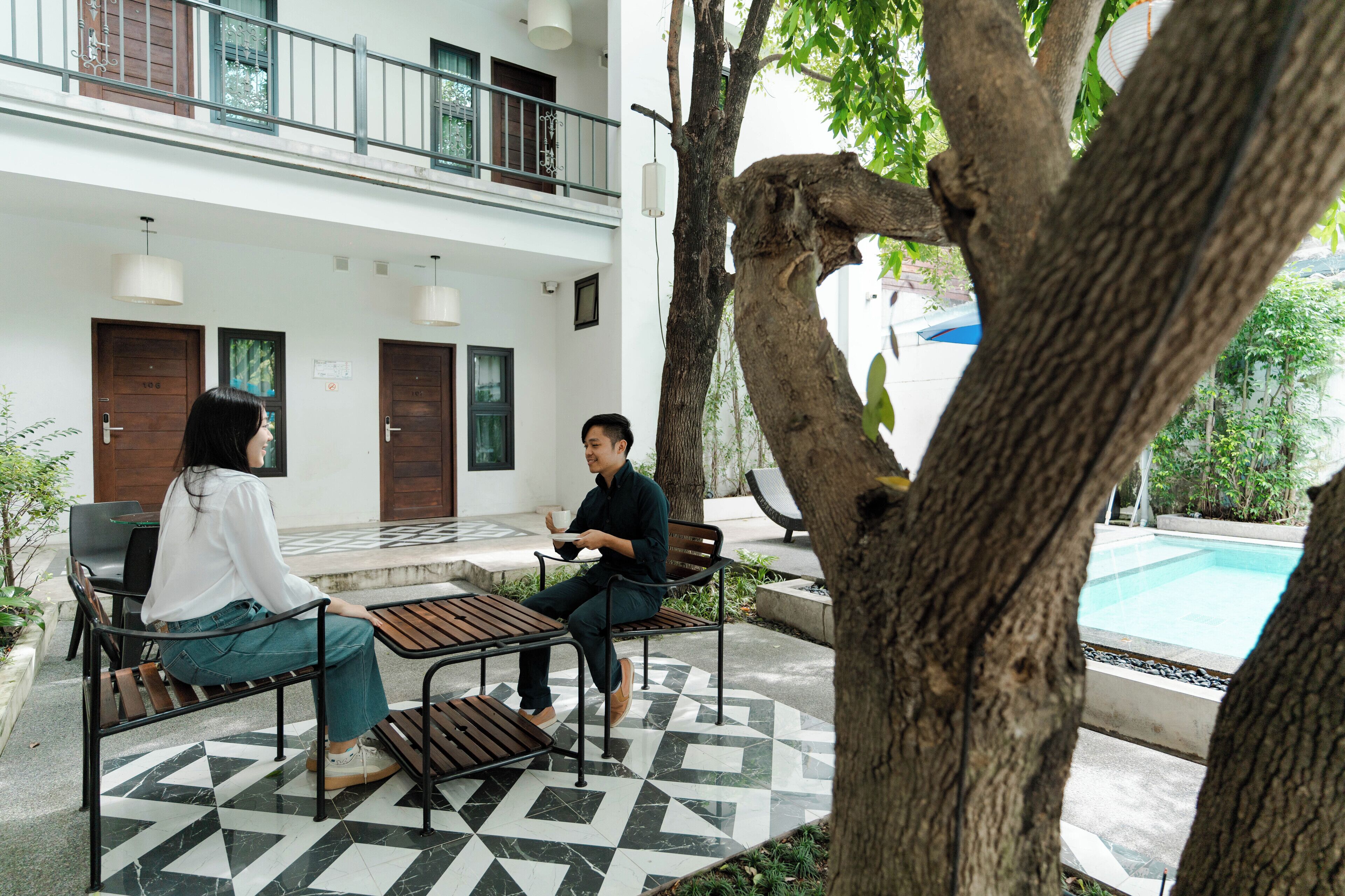 A courtyard with a pool, two wooden doors, and a tree.