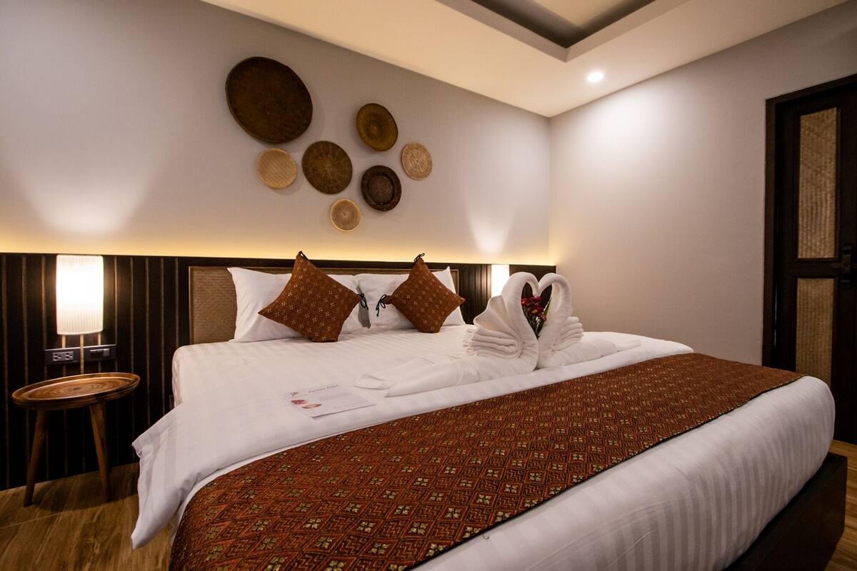 Una habitación de hotel con una cama grande, una mesita de noche, una lámpara y decoración mural.
