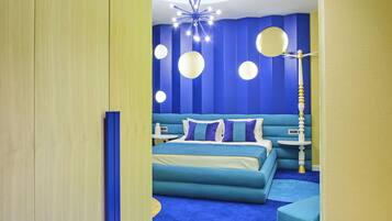 A modern bedroom with a blue and yellow color scheme, featuring a bed, a circular window, and a unique ceiling light fixture.