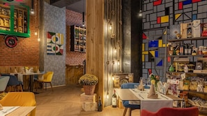 Interior de restaurante com pisos de madeira, paredes de tijolo e diversas opções de assento, incluindo mesas e cadeiras.
