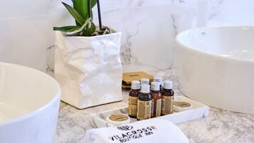 A bathroom with a large white sink, a marble countertop, a white vase with orchids, and a towel with text.