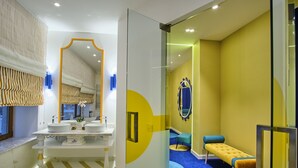 Um banheiro moderno com um espelho grande, duas pias, um banco e um tapete azul.
