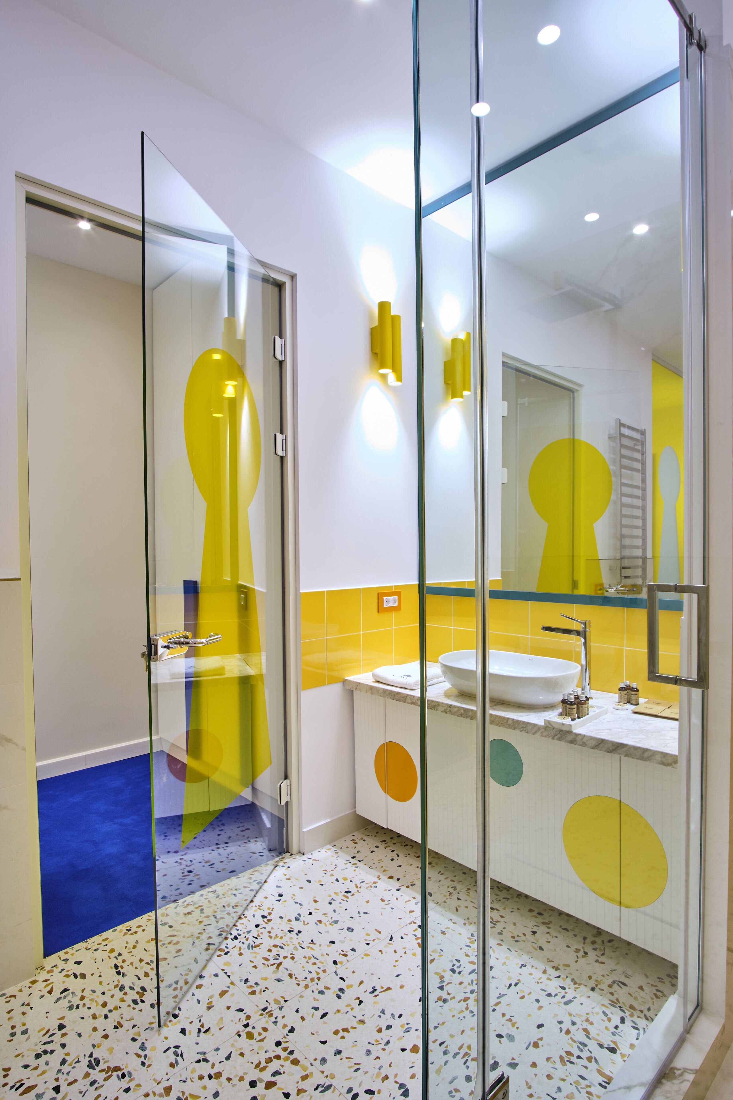 Un baño moderno con separador de vidrio, lavamanos y espejo.