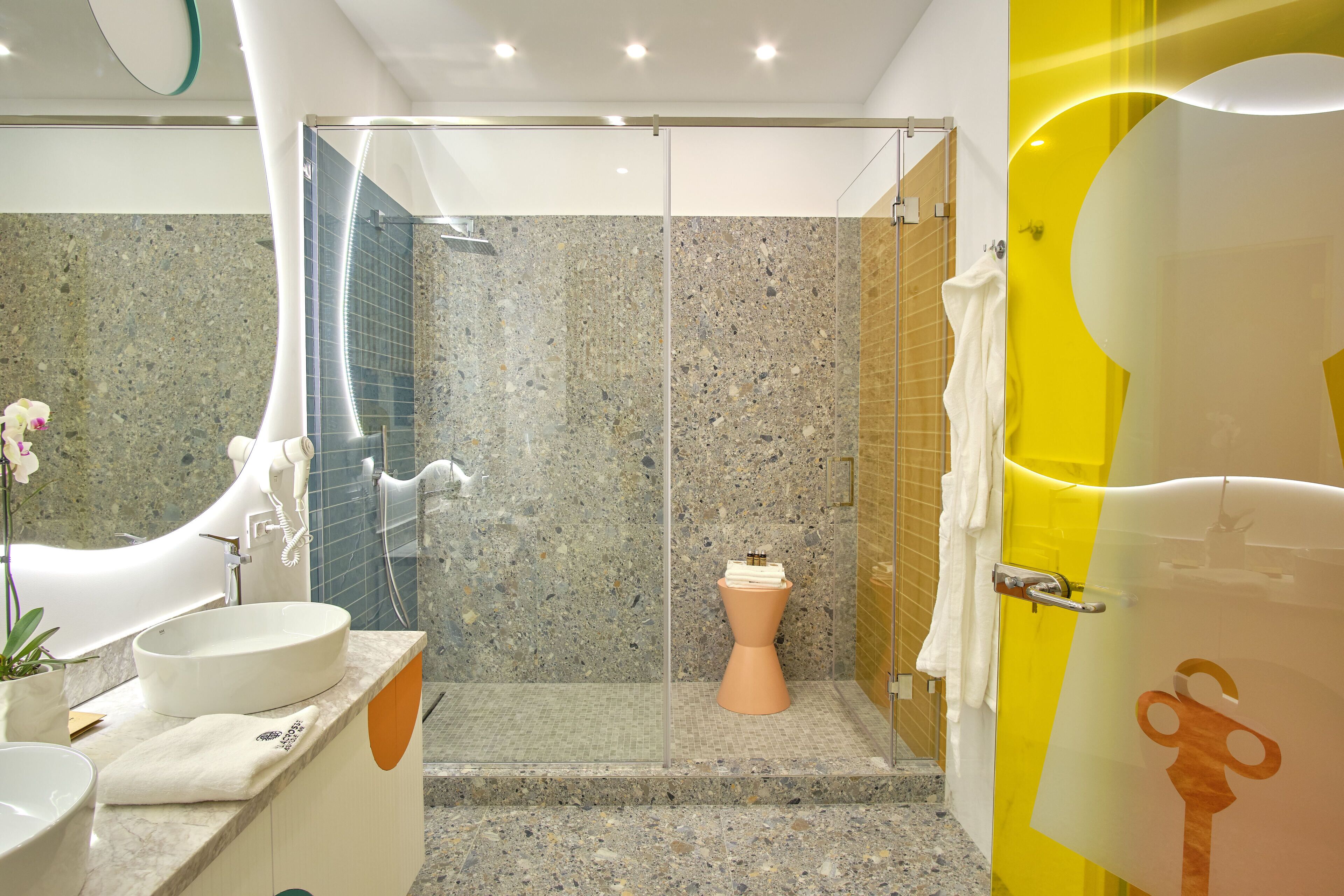 Un baño moderno con ducha de vidrio, lavamanos blanco y un diseño de inodoro original.