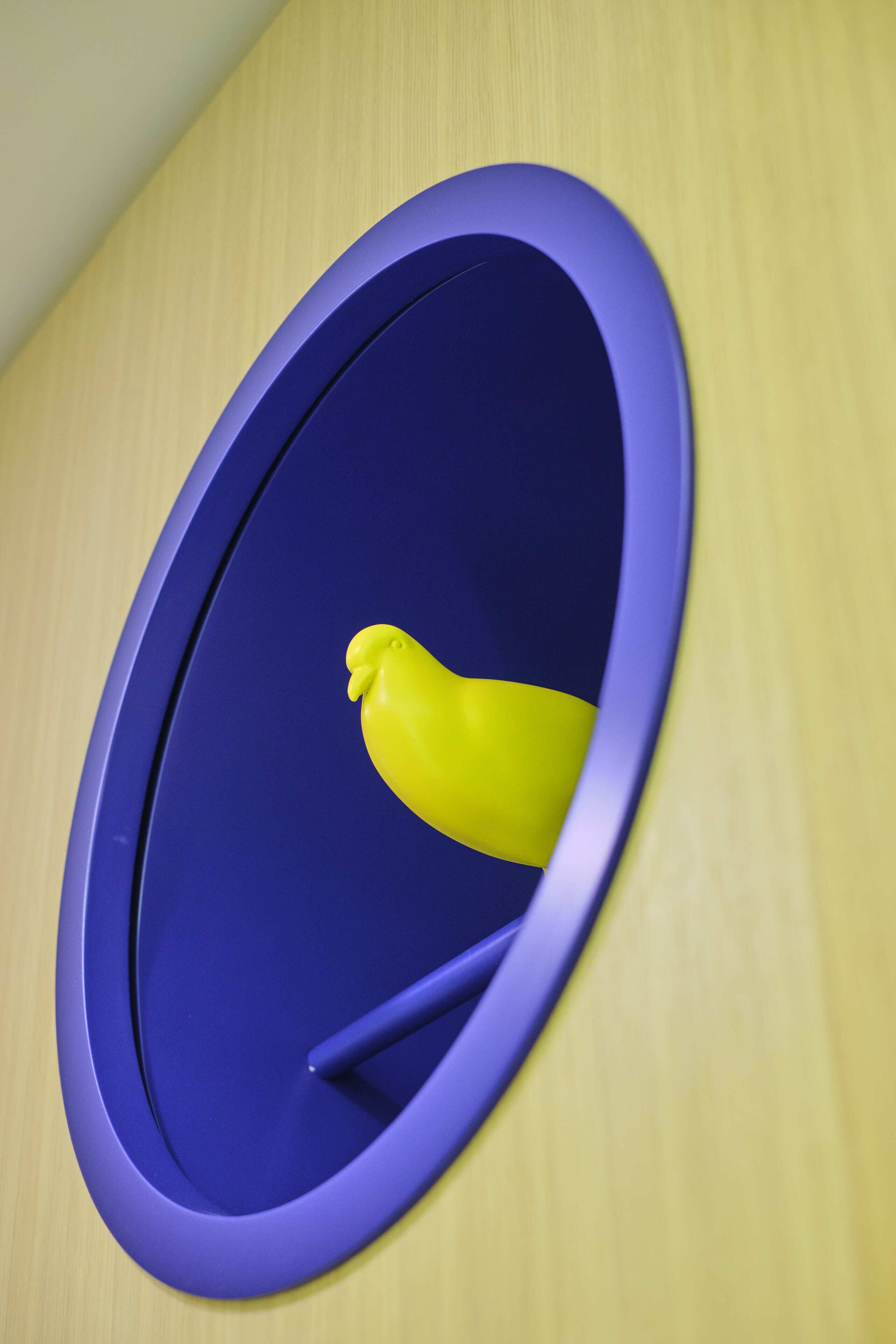 A bathroom with a blue oval mirror and a yellow rubber duck.