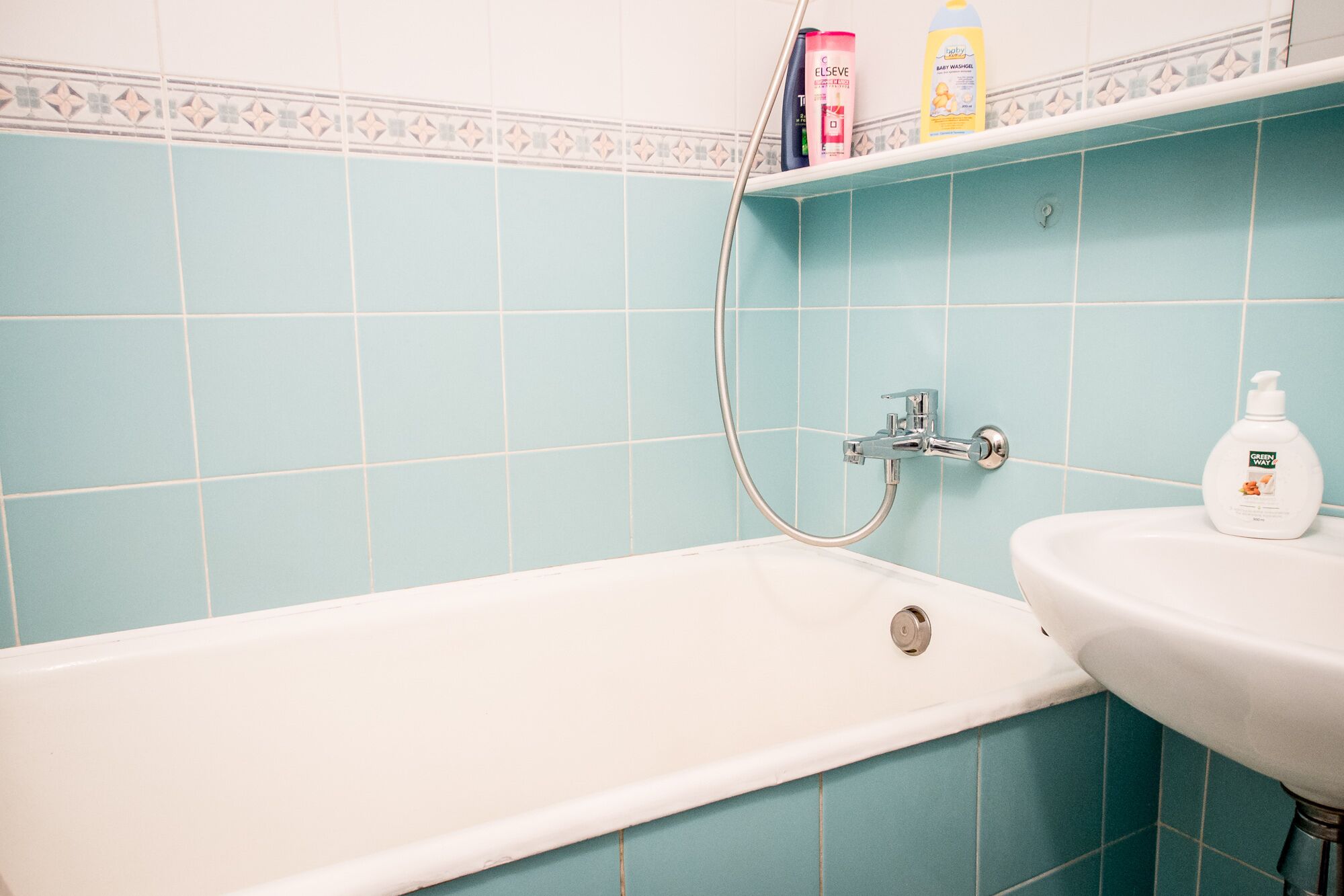 Une salle de bain équipée d’une baignoire, d’un lavabo et d’un flexible de douche.