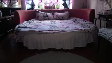 Une chambre à coucher avec un grand lit, une tête de lit rouge et une fenêtre avec des rideaux.