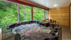 A hot tub with a view of lush greenery through large windows. - Sky Wind and Star SPA Pension (Pocheon)