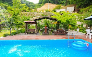 A swimming pool with a wooden deck, a gazebo, picnic tables, and a small garden area. - Sky Wind and Star SPA Pension (Pocheon)