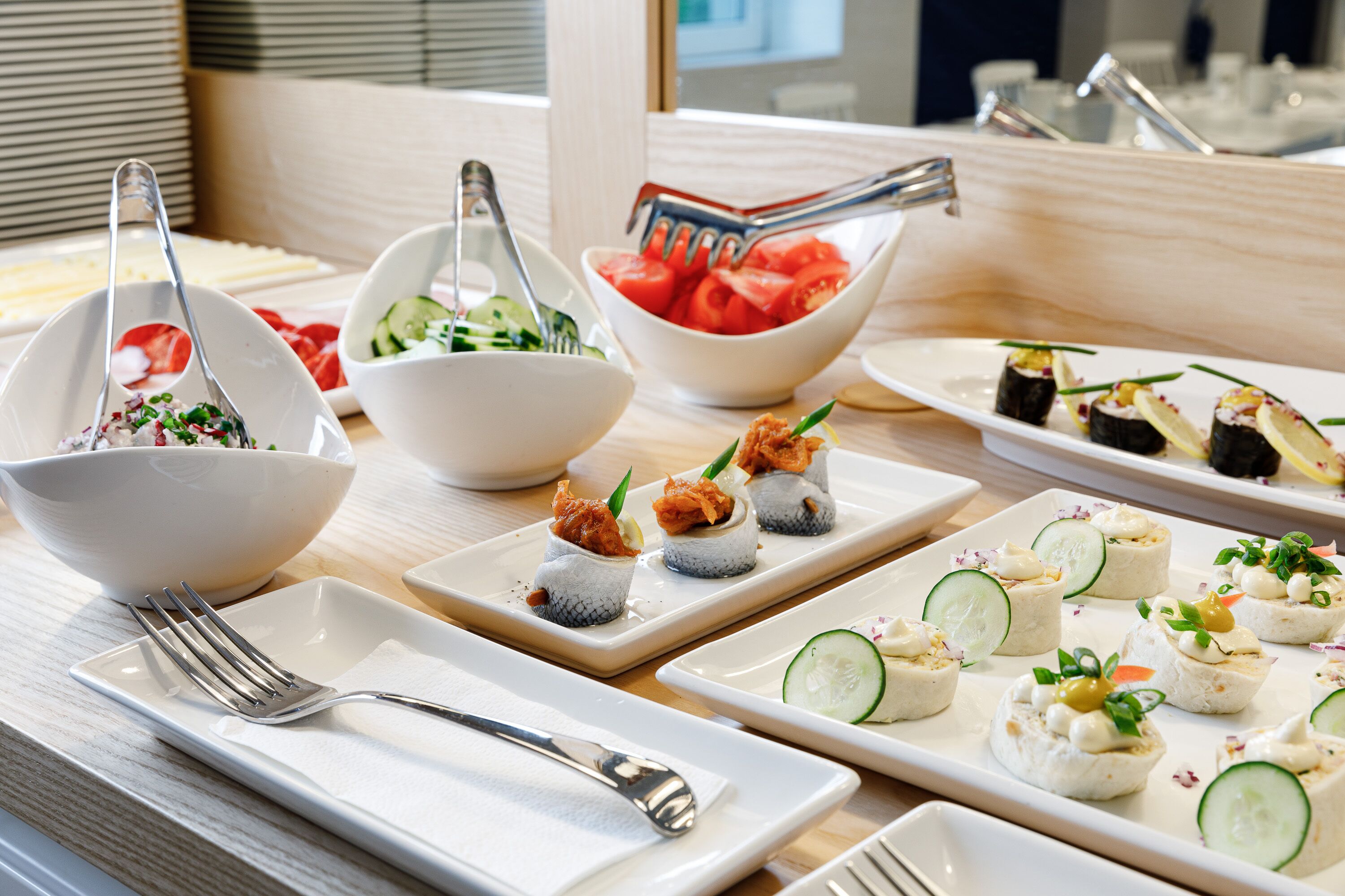 Una mesa de buffet con diversos platos, como sushi, ensaladas y aperitivos.